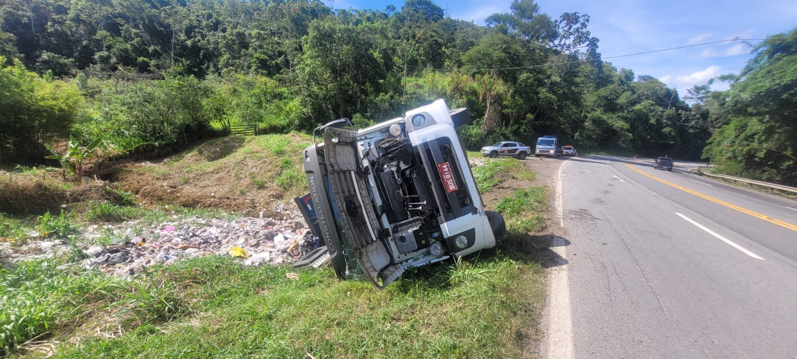 Caminhão carregado de lixo tomba e deixa motorista ferido na BR-040 em Santos Dumont